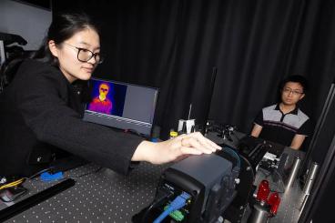 Postdoctoral scholar Dingding Han adjusts a thermal camera capturing an image of Ph.D. student Corey Zheng.